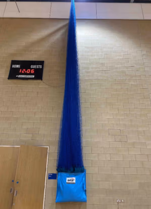 Wall mounted PVC storage bags for sports hall division nets and cricket netting installed in indoor sports facility