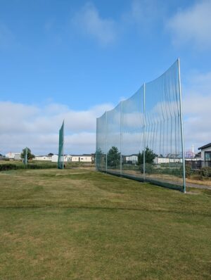 In-ground socketed protection netting system installed around an outdoor sports facility